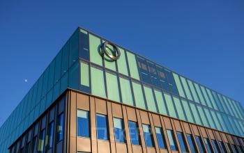 Modern exterior of an office building at Fred. Roeskestraat 115, Amsterdam Zuidas, featuring a sleek glass facade, with the moon visible in the background. Office space rental available.
