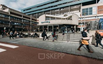 Exterior view of a modern office building at De Boelelaan 1110, Amsterdam Zuidas, with people walking and sitting outside.