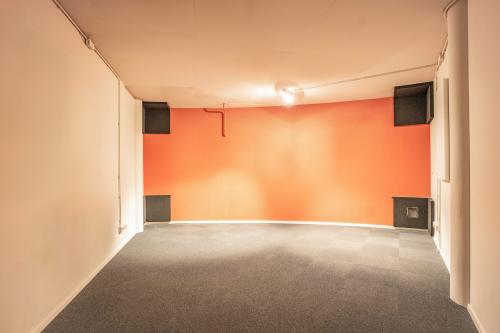 An empty office space with a curved, orange accent wall and carpet flooring at De Boelelaan 1110, ideal for office space rental in Amsterdam Zuidas.