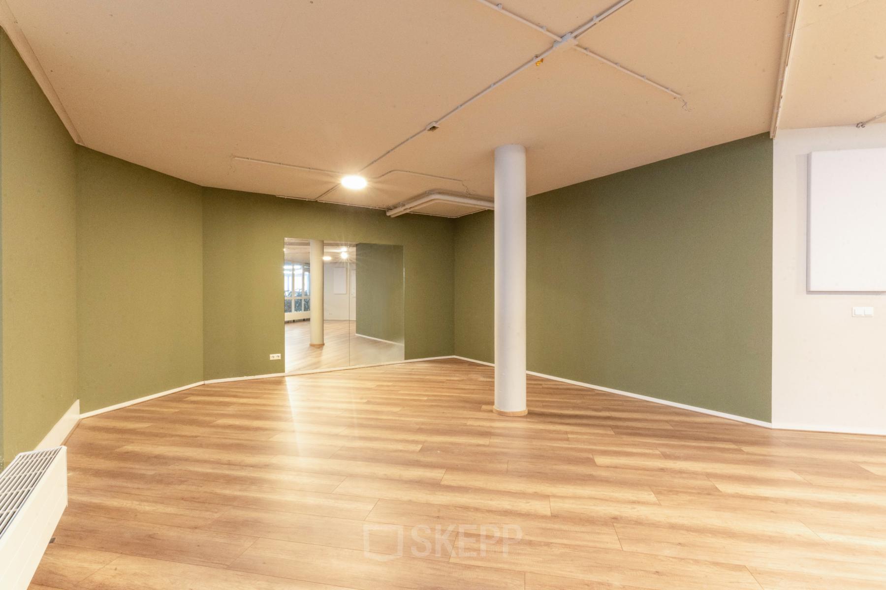 Spacious office interior at De Boelelaan 1110, Amsterdam Zuidas featuring wooden floors and green walls, ideal for office space rental.