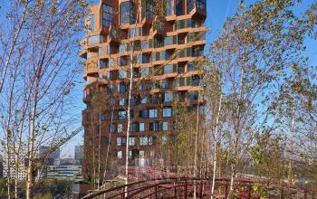 Exterior view of an office building at Hildegard Von Bingenstraat 44, Amsterdam Zuidas. Office space rental available with a unique architectural design surrounded by trees and walkways.