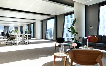 Bright office space for rent in Amsterdam Zuidas with large windows, modern furniture, and plants, perfect for an inspiring work environment.