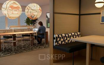 A furnished office space with a person using a laptop at Barbara Strozzilaan 101 101, Amsterdam Zuidas. Ideal for office space rental, featuring modern seating and decorative lighting.