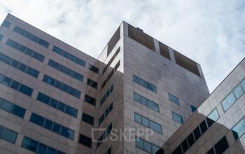 A tall, modern office building with a geometric design at Barbara Strozzilaan 101, perfect for those seeking office space rental in Amsterdam Zuidas.