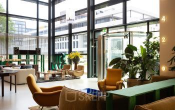 Spacious and well-lit office interior at Barbara Strozzilaan 101 in Amsterdam Zuidas, featuring modern furniture and large windows, ideal for office space rental.