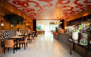 Lively office space rental with eclectic decor at Barbara Strozzilaan 101, Amsterdam Zuidas. Two people are working at tables in this furnished lounge area.