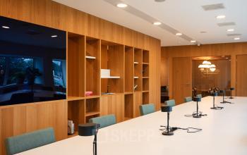 Modern workspace featuring a long table with task lamps and seating in Amsterdam Zuidas, ideal for office space rental.