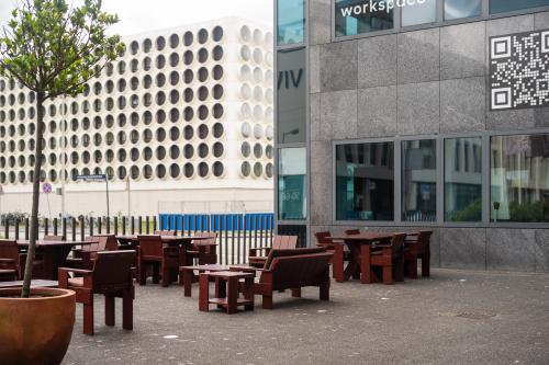 Outdoor seating area at Barbara Strozzilaan 101, Amsterdam Zuidas, featuring wooden benches and tables, ideal for breaks or informal meetings. Discover office space rental options for your business needs.