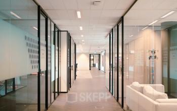 Modern office interior at Jachthavenweg 109, Amsterdam Zuidas, featuring glass-walled corridors ideal for office space rental.
