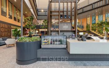 Modern office space at Jachthavenweg 109 in Amsterdam Zuidas featuring a stylish reception area with a beverage cooler and plants, ideal for those seeking office space rental.