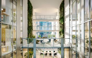Bright multi-level office space at Claude Debussylaan 80-134, Amsterdam Zuidas with lush greenery and glass walls, available for rent. A modern interior setup offering ample natural light for rentals.