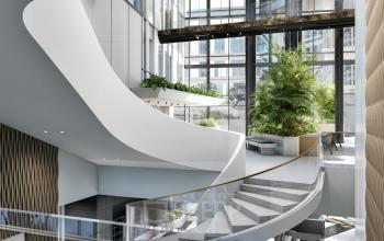 Bright office interior at Claude Debussylaan 80-134, Amsterdam Zuidas, featuring modern architecture, open stairway, and lush plants, perfect for office space rental with a refreshing ambiance.