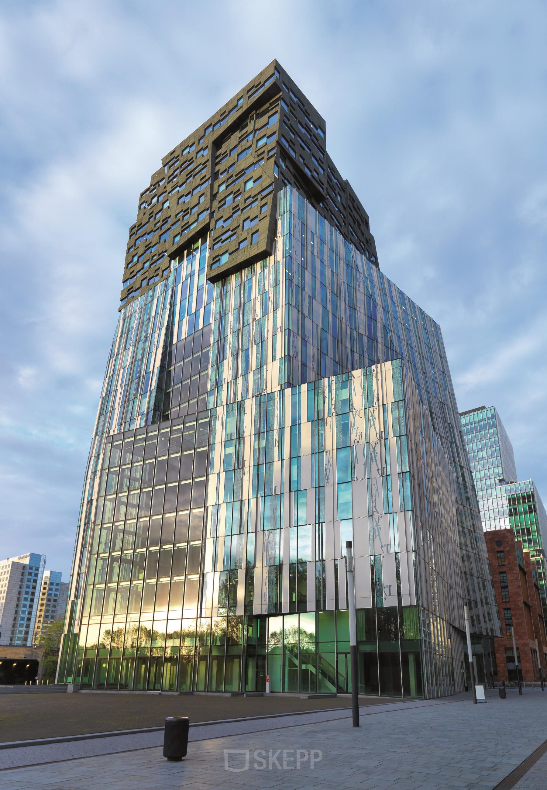 Modern glass office building in Amsterdam Zuidas, featuring a striking facade at Claude Debussylaan 80-134, suitable for office space rental.