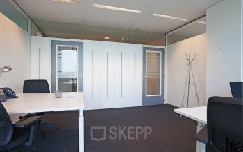 Modern office space rental with glass partitions at Gustav Mahlerplein 2, Amsterdam Zuidas, featuring ample natural light and ergonomic furnishings.