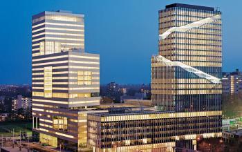 Modern office building complex at Gustav Mahlerplein 2, Amsterdam Zuidas, ideal for office space rental with illuminated windows creating a vibrant business atmosphere.