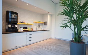 Modern pantry area with coffee machine, counter space, and minimalistic storage at office to rent on Gustav Mahlerplein 2, Amsterdam Zuidas.