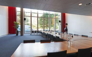 Bright and spacious conference room at Gustav Mahlerplein 2, Amsterdam Zuidas, featuring large windows, long tables, black chairs, and modern decor. Ideal office space rental for meetings.