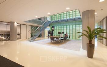 Sleek and modern office space rental at Gustav Mahlerplein 2, Amsterdam Zuidas with a professional team actively engaged in a business meeting.