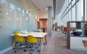 Modern office space for rent at Gustav Mahlerplein 2, Amsterdam Zuidas with large windows, vibrant furniture, and multiple work areas.