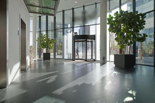 Spacious entrance lobby at Gustav Mahlerplein 2, Amsterdam Zuidas with large glass windows, potted plants, and a revolving door.