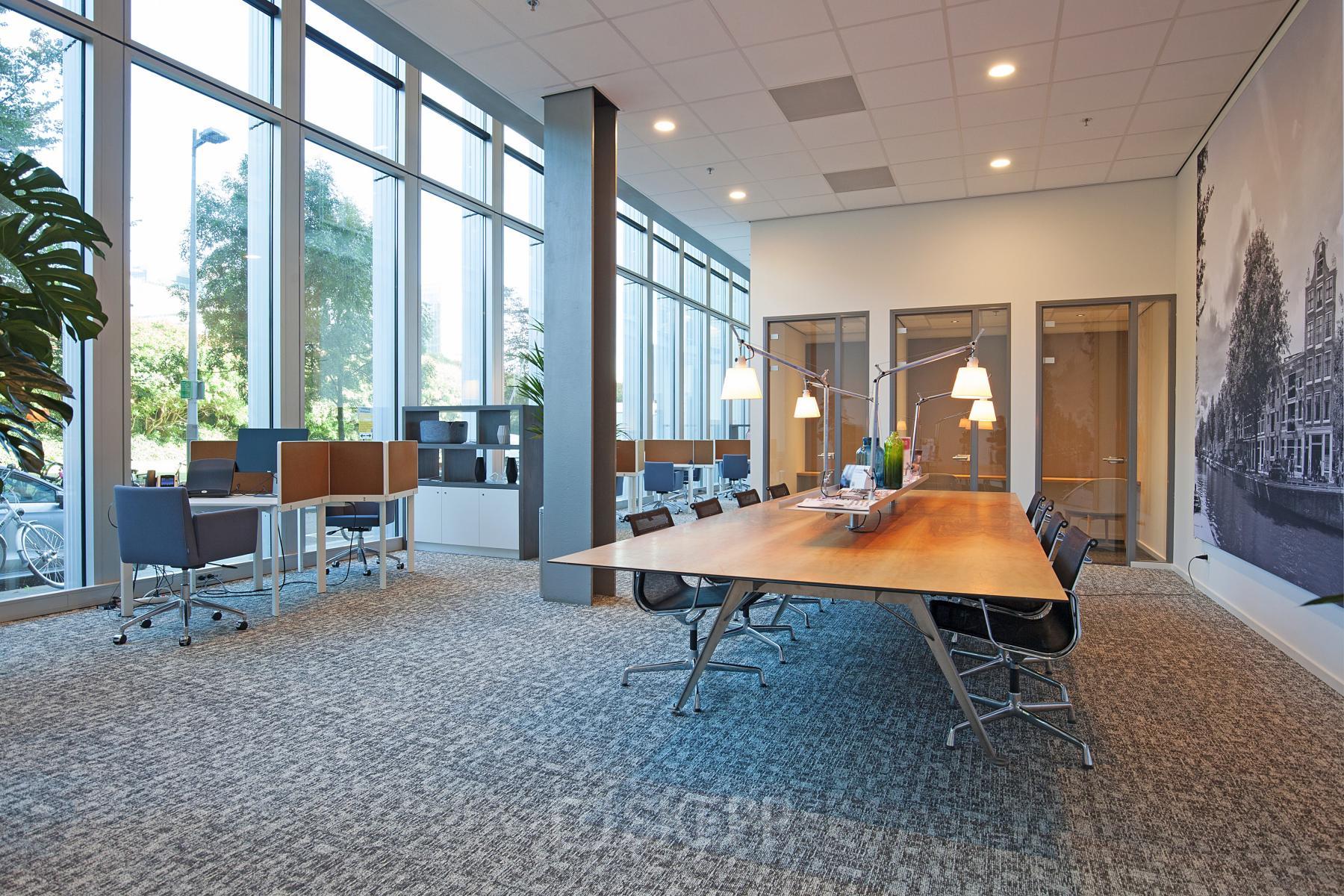 Modern and spacious office to rent at Gustav Mahlerplein 2 in Amsterdam Zuidas, featuring large windows, stylish furnishings, and a collaborative workspace.