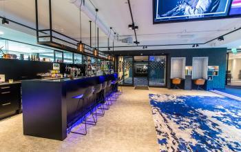 Modern office space for rent at Gustav Mahlerplein 28 & 58-60, Amsterdam Zuidas, featuring a stylish bar area with high stools and a vibrant carpet.