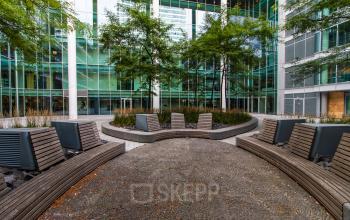 Outdoor seating area with modern benches and greenery at Gustav Mahlerplein, perfect for a break near your office space rental in Amsterdam Zuidas.