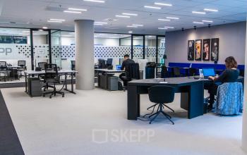 Modern office space rental at Gustav Mahlerplein in Amsterdam Zuidas with people working on laptops at desks, featuring open workspaces with contemporary furniture.