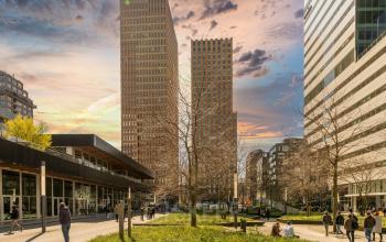 Exterior view of the office building located at Gustav Mahlerplein 109-115, Amsterdam Zuidas, showing tall structures with a plaza and people walking.