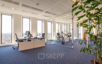 Spacious and well-lit office space for rent at Gustav Mahlerplein 109-115 in Amsterdam Zuidas, featuring modern desks, large windows, and indoor plants.