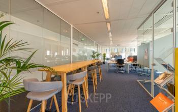 Bright office space at Gustav Mahlerplein 109-115, Amsterdam Zuidas, featuring high stools and desks, open workspace with glass partitions.