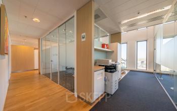 Interior office view at Gustav Mahlerplein 109-115, Amsterdam Zuidas with glass-walled meeting rooms, wooden floors, and office equipment.