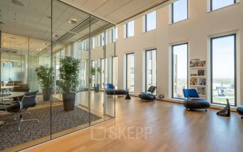 Spacious office interior with large windows, glass-walled conference room, modern furnishings, and wooden flooring at Gustav Mahlerplein 109-115, Amsterdam Zuidas.