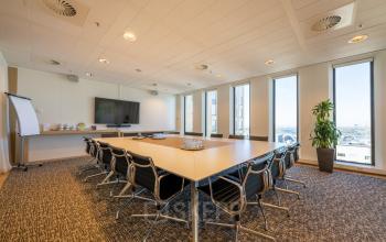Spacious conference room with large windows, modern furnishings, and a central table, located at Gustav Mahlerplein 109-115, Amsterdam Zuidas.