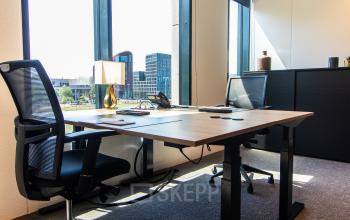 Modern office space at Gustav Mahlerlaan 1212, Amsterdam Zuidas, featuring large windows, two desks, and office chairs, with a view of the cityscape.