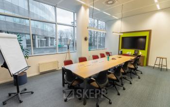 Vergaderruimte in kantoor te huur op Uitbreidingstraat 84, Antwerpen Berchem, met grote ramen, moderne stoelen, een lange tafel, en een televisie.