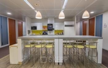 Kantoorruimte te huur met een moderne kitchenette en hoge tafels met krukken, ideaal voor informele vergaderingen en koffiepauses. Gelegen op Uitbreidingstraat 84, Antwerpen Berchem.