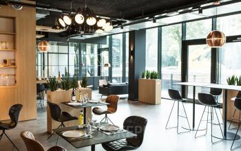 Moderne gemeubileerde kantoorruimte te huur op Uitbreidingstraat 66, Antwerpen Berchem, met grote ramen, natuurplanten en verschillende tafels en stoelen.