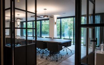 Moderne, verlichte vergaderruimte met glazen wanden in een kantoor te huur op Uitbreidingstraat 66, Antwerpen Berchem. Grote ramen bieden uitzicht op groen.