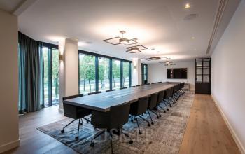 Vergaderruimte in kantoor te huur in Uitbreidingstraat 66, Antwerpen Berchem. Lange tafel met stoelen, grote ramen met uitzicht op buiten.
