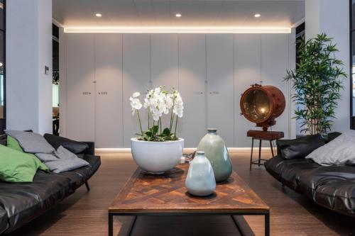 Modern lounge area with black leather sofas, a wooden coffee table, decorative vases, and an orchid at Uitbreidingstraat 66, Antwerp Berchem, featuring office space rental.