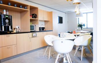 Modern pantry area at De Keyserlei 58-60 in Antwerp Center, featuring a coffee machine, microwave, sink, and stylish seating for office space rental.
