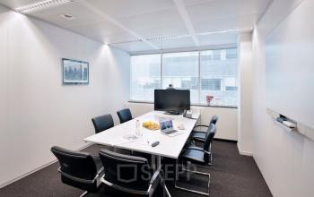 Modern conference room available for office space rental at Lange Lozanastraat 142, Antwerp Center, featuring a sleek table, black chairs, and a large screen.