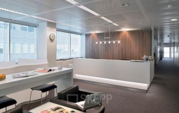 Modern office space with sleek furnishings at Lange Lozanastraat 142, Antwerp Center, perfect for office space rental. Features a long white desk and lounge chairs.