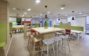 Een moderne gemeubileerde kantoorruimte te huur op Noorderlaan 147 in Antwerpen Merksem, met kleurrijke meubels en lichte houten vloeren.