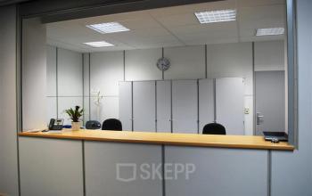 Reception area with a wooden counter, phone, note pad, and plant at Boomsesteenweg 690, Antwerp Wilrijk, Antwerp.