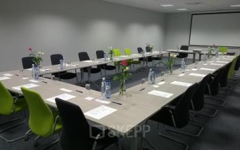Conference room at Boomsesteenweg 690, Antwerp Wilrijk with long tables arranged in a U-shape, chairs, and presentation screen suitable for office space rental.