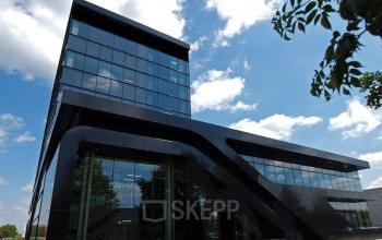 Modern zwart kantoorgebouw gelegen op Nijverheidsstraat 70, Antwerpen Wommelgem, Antwerpen. Het gebouw heeft een opvallende glazen gevel en een uniek ontwerp met schuine lijnen. Kantoorruimte te huur beschikbaar.