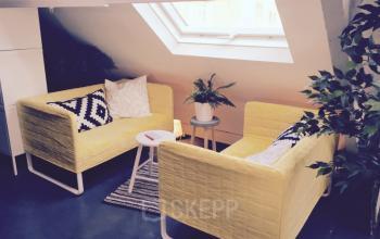 Modern office lounge area with yellow sofas, a small table, and a skylight window at Grote Hondstraat 44, Antwerp Zurenborg.