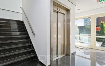 Bright interior of an office building in Apeldoorn at Linie 580-596, showing an elevator and stairs with large windows that allow natural light.